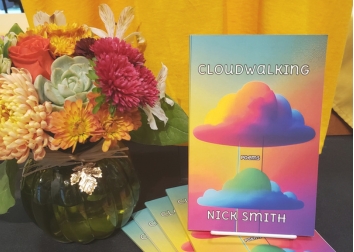 A book on a table with a fall arrangement of flowers.