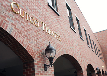 Gold letters that say "Cutco Theater" on an exterior brick wall of a building.