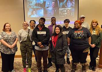 Winners of a JCC poetry contest stand together in front of a projector screen.