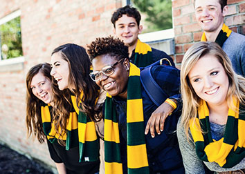 Six students wearing scarves smile and laugh