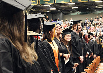 Students wearing caps and gowns standing in the gym