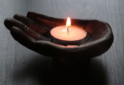 A small sculpted hand holding a tealight candle.