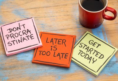 Colorful sticky notes on a table with a coffee mug that read "Don't procrastinate," "Late is too late," and "Get started today."