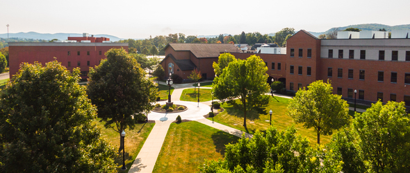 An arial view of buildings and trees, with sidewalks and the clocktower in the center of the Cattaraugus County Campus.