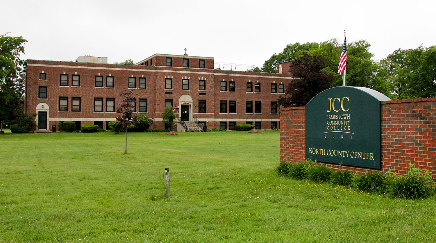 North County Center Main Building, surrounded by green lawn, with the green NCC sign with gold lettering in front of the building