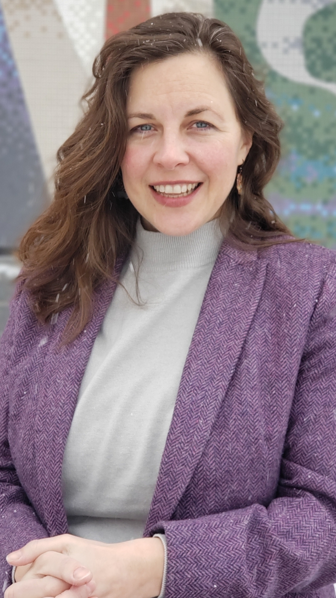 Dean Jessica Kubiak stands against a brick mosaic background.