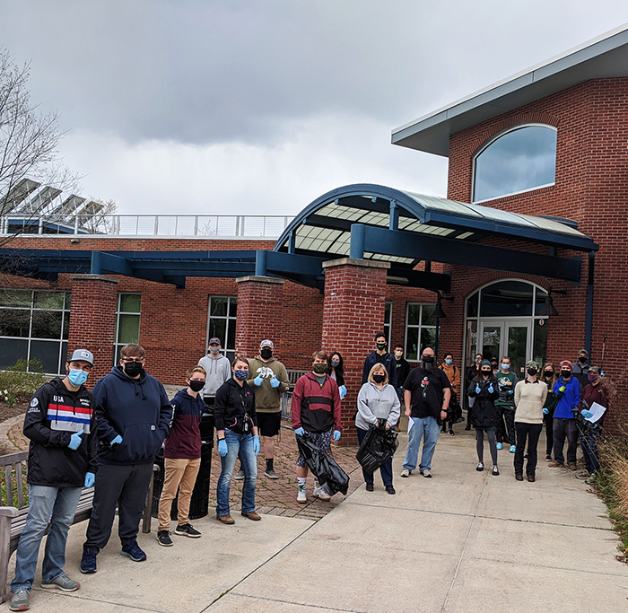 Students, faculty, and staff waering masks and gloves stand with garbage bags in front of JCC's Science Center.