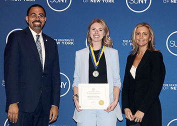 Chancellor King stands with Mikayla Moshier, who is wearing a medal and holding a certificate, and Sarah Tranum.