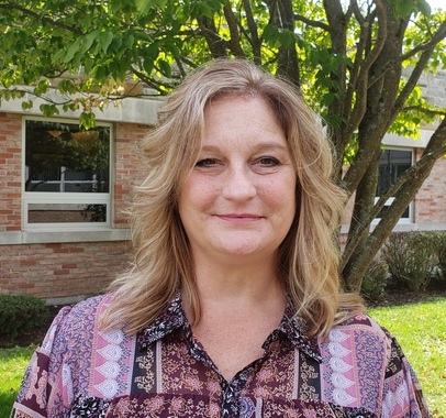 A woman standing in front of a brick building.